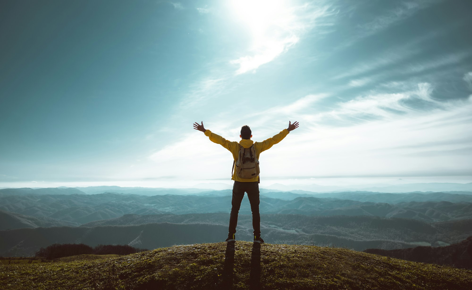 Hiker with arms up standing on the top of the mountain